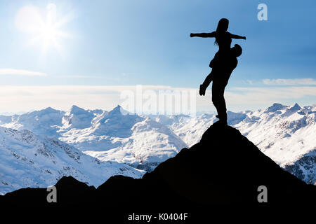 Silhouette Of Man Carrying Her Girlfriend Standing On The Top Of Snow Mountain Stock Photo