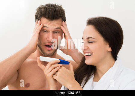 Portrait Of Young Couple Looking At Pregnancy Test Over White Background Stock Photo