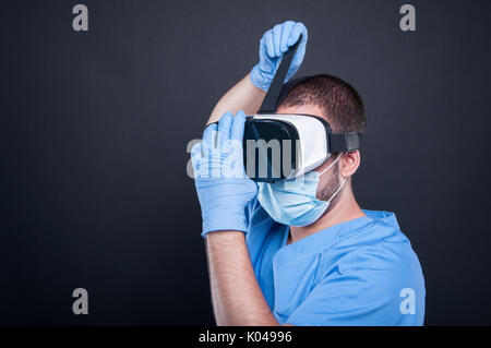 Surgeon wearing scrubs putting on vr goggles on black background Stock Photo