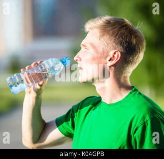 Tired man drinking water from a plastic bottle after fitness Stock Photo