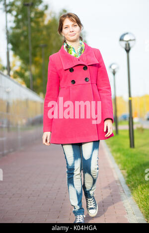 Beautiful woman in red coat walking autumn street.  Stock Photo