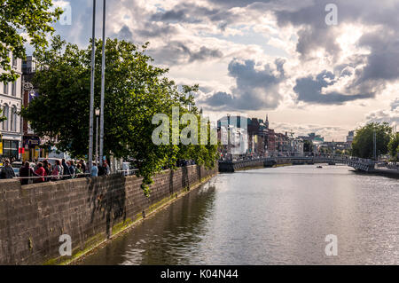 People cross Ha'Penny Bridge across the River Liffey in the Irish capital city, Dublin Stock Photo