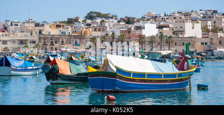Traditional fishing boats floating in Marsaxlokk harbour on the island of Malta. The boats are made of wood and painted in tradition colours. Stock Photo