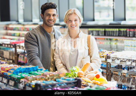 Portrait smiling young couple grocery shopping in market Stock Photo
