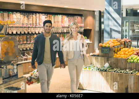 Portrait young couple holding hands, grocery shopping in market