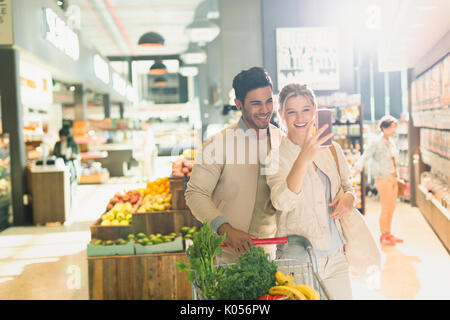 Smiling young couple taking selfie in grocery store market Stock Photo