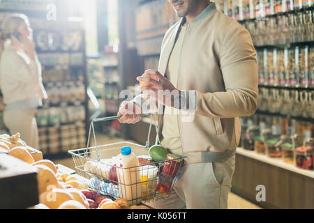 Young man grocery shopping, examining fruit in market Stock Photo