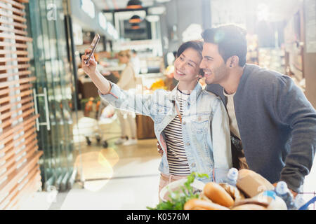 Young couple taking selfie grocery shopping in market