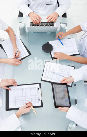 Cropped image of doctors examining medical reports at desk in clinic Stock Photo