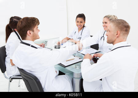 Doctors shaking hands at desk in clinic Stock Photo