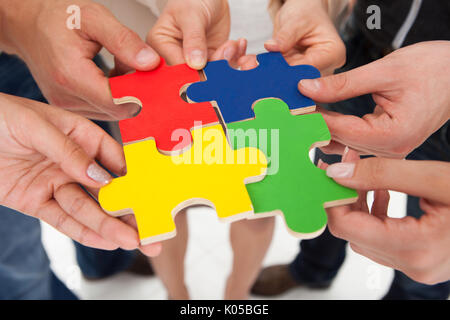 Cropped image of businesspeople joining puzzle pieces in office Stock Photo