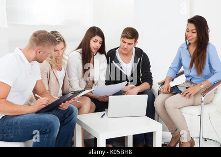 Group of businesspeople discussing over documents in office Stock Photo