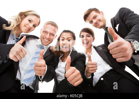 Low angle portrait of business people gesturing thumbs up against white background Stock Photo