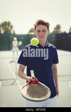 Young male tennis player bouncing tennis ball on tennis racket on tennis court Stock Photo