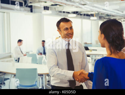 Businessman shaking hands with businesswoman in office Stock Photo