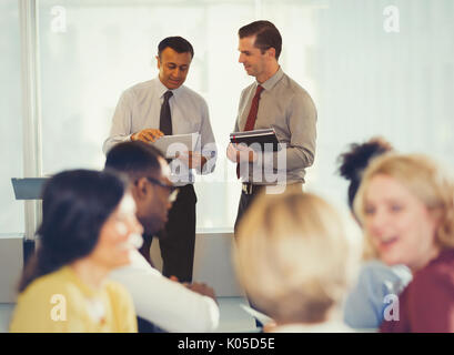 Businessmen discussing paperwork at conference Stock Photo