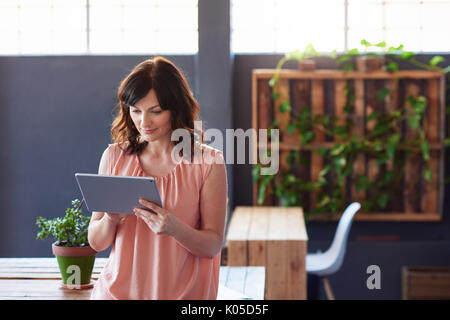 Businesswoman standing in an office using a digital tablet Stock Photo