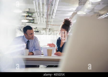 Businessman and businesswoman discussing paperwork in office meeting Stock Photo