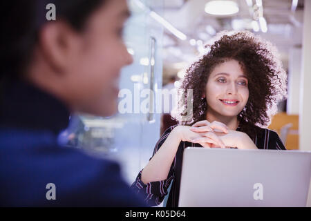 Smiling businesswoman at laptop listening in conference room meeting Stock Photo