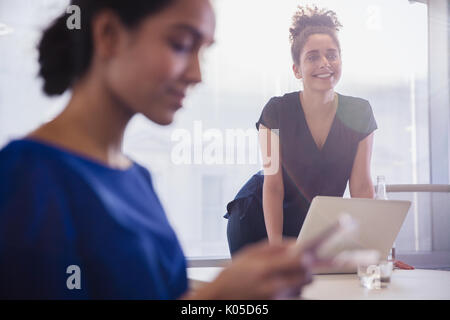 Smiling businesswoman leaning at laptop in conference room meeting Stock Photo