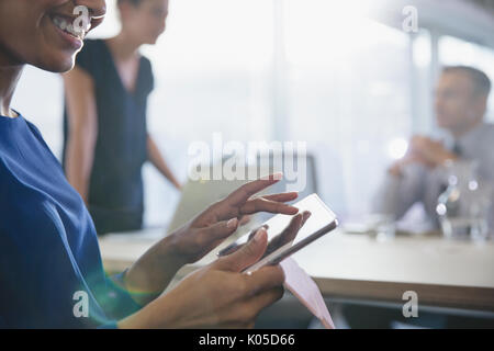 Close up smiling businesswoman using digital tablet in conference room meeting Stock Photo