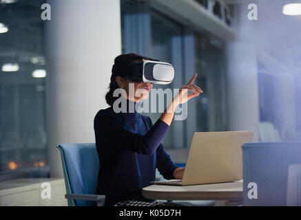 Businesswoman using virtual reality simulator at laptop in office Stock Photo
