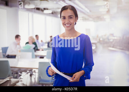 Portrait smiling businesswoman with paperwork in office Stock Photo