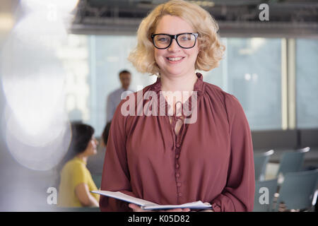 Portrait smiling, confident businesswoman with paperwork in office Stock Photo