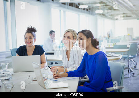 Businesswomen at laptops listening in office meeting Stock Photo