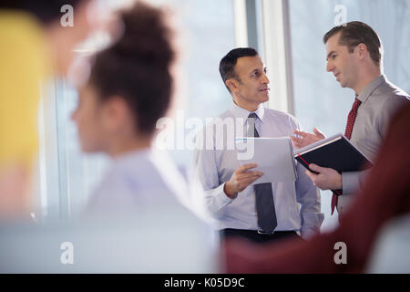 Businessmen talking in office window Stock Photo