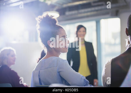 Businesswoman turning, listening in conference audience Stock Photo