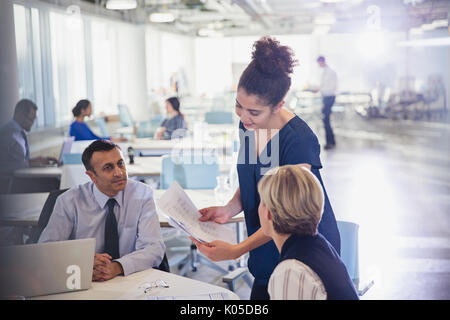 Businesswoman discussing paperwork with colleagues in office meeting Stock Photo