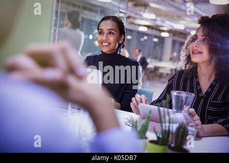 Smiling businesswomen listening in conference room meeting Stock Photo