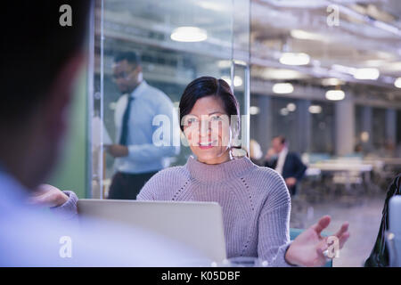 Businesswoman gesturing, talking at laptop in conference room meeting Stock Photo