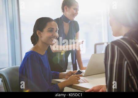 Smiling businesswomen talking in conference room meeting Stock Photo
