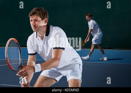 Focused male tennis doubles players playing tennis on tennis court Stock Photo