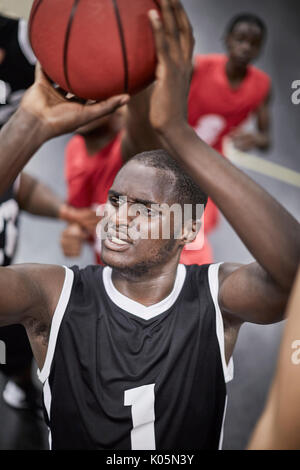 Focused young male basketball player shooting the ball Stock Photo
