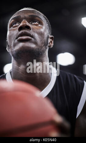 Close up focused young male basketball player with basketball looking up Stock Photo