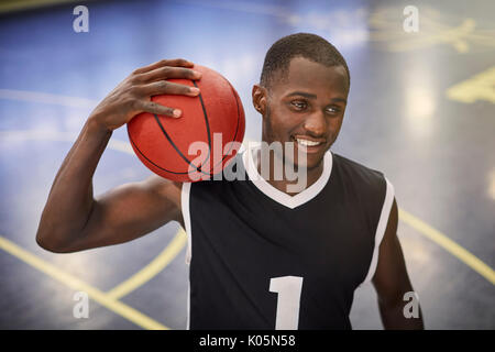 Confident young male basketball player holding basketball on court Stock Photo