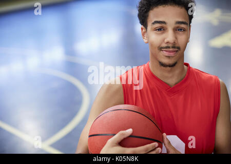 Portrait confident young male basketball player holding basketball on court Stock Photo
