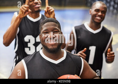 Portrait smiling, confident young male basketball player team in black jerseys gesturing, celebrating victory Stock Photo