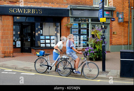 senior couple on bicycles looking in estate agents windows Stock Photo