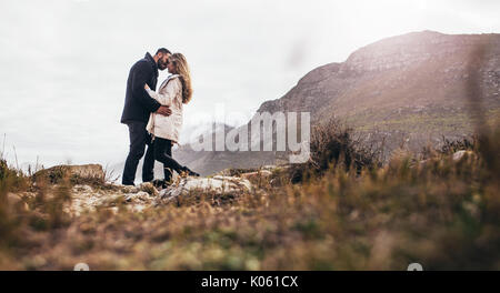 Romantic couple kissing in the nature. Horizontal shot of passionate couple on the beach during winter holidays. Stock Photo