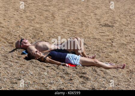 West Bay, Dorset, UK. 21st August 2017.   UK Weather.  Sunbathers enjoying the warm sunny weather on the beach at the seaside resort of West Bay in Dorset as summer makes an appearance after weeks of unsettled conditions.  Photo Credit: Graham Hunt/Alamy Live News Stock Photo