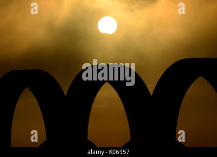 Partial Eclipse viewed briefly through hazy cloud over the silhouette of the Olympic Rings, Portland, Dorset, UK Credit: Finnbarr Webster/Ģ����ý Live News Stock Photo