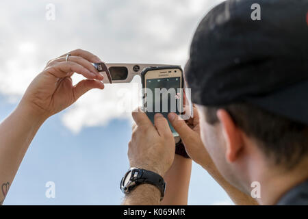 Vernon, Alabama, USA. 21st Aug, 2017. Using solar eclipse glasses as a shield, folks were doing their best to capture a photo of the Solar Eclipse on Monday Aug. 21st 2017. These people were outside the Pizza Hut in Vernon, Alabama. Credit: Tim Thompson/Alamy Live News Stock Photo