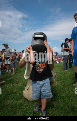 Amherst, USA. 21st Aug, 2017. young boy watches eclipse with neighbor’s welding helmet in Amherst MA Credit: Edgar Izzy/Alamy Live News Stock Photo