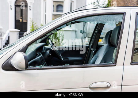 Close up of passenger side window of small white car smashed after robbery. Stock Photo