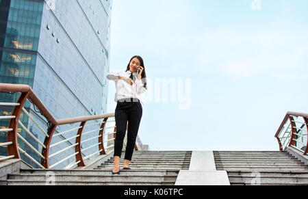 Business woman checking time while having phone call Stock Photo