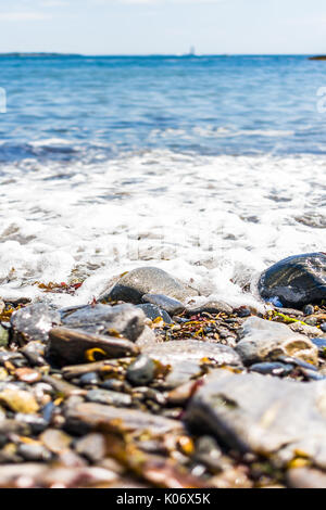 Rocky public beach called Ship Cove by Portland Head Lighthouse in Cape Elizabeth, Maine with closeup of water and stones on ground level Stock Photo